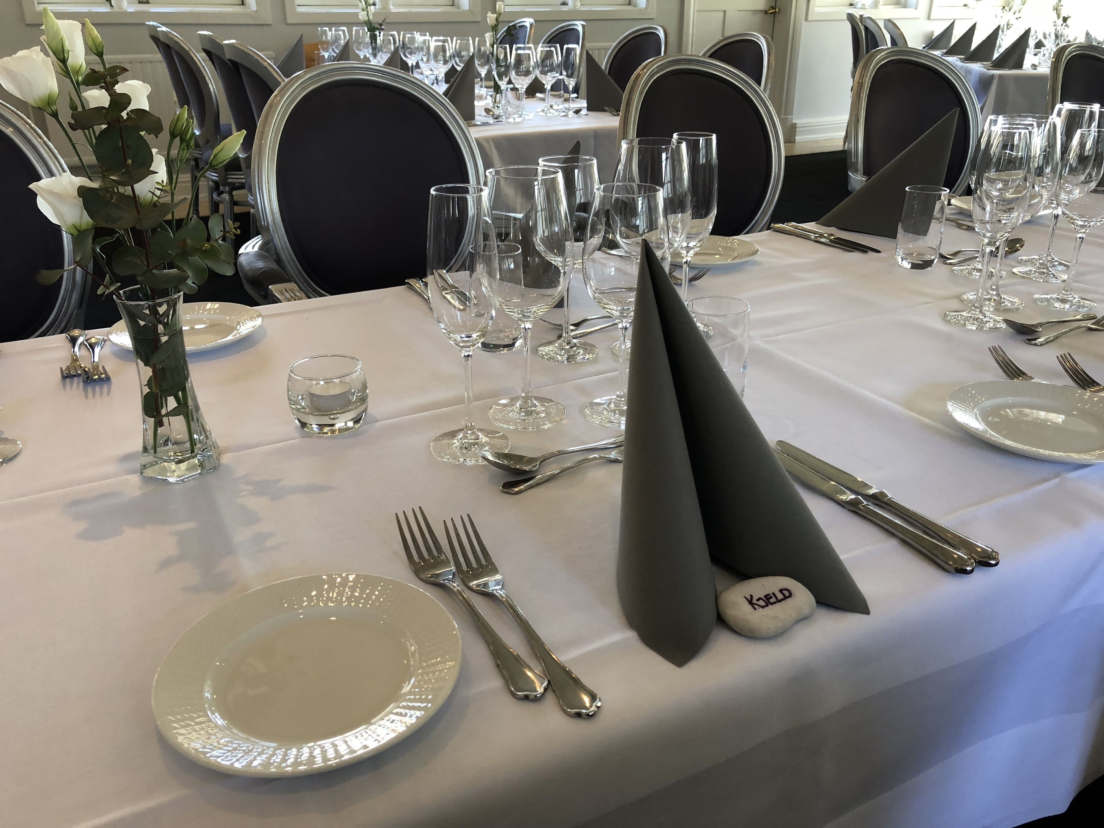 A table set for a formal dining event with a white tablecloth, silverware, and clear glassware.