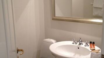 A small bathroom with a toilet, sink, and mirror.