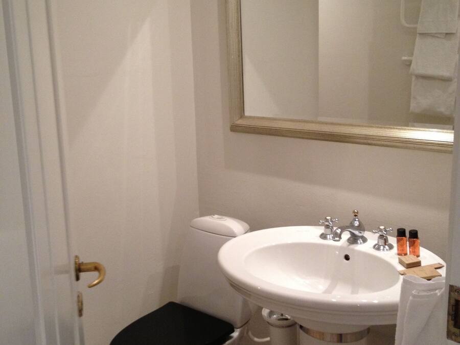 A small bathroom with a toilet, sink, and mirror.