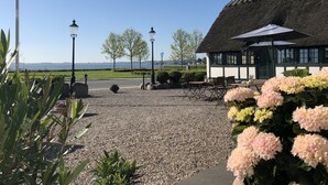 A building with a thatched roof, outdoor seating, and a view of the sea. - Munkebo Kro (Munkebo)