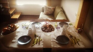 Un tavolo da pranzo apparecchiato con piatti, posate e una ciotola di frutta in un accogliente soggiorno.
