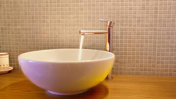 Un lavamanos de baño con una llave moderna y un salpicadero de azulejos.