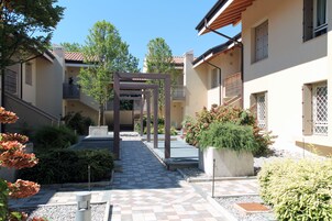 Un cortile con un vialetto di piastrelle a scacchi, una pergola e piante in vaso.