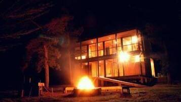 A modern, multi-story building at night with illuminated windows, surrounded by trees.