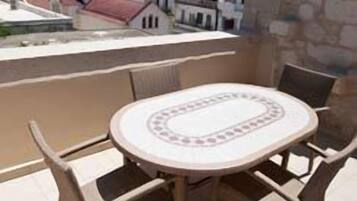 A round table with four chairs on a terrace with a view of a cityscape.