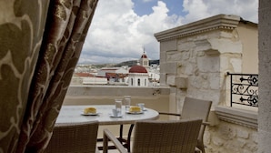A balcony with wicker chairs and a table set for two, overlooking a cityscape with historic buildings and a red-domed church. - Antica Dimora Suites (Rethymno)
