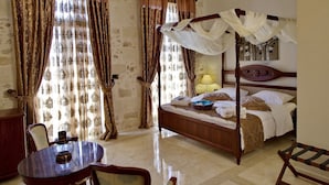 A four-poster bed with a canopy, a bedside table, a lamp, and a chair. - Antica Dimora Suites (Rethymno)
