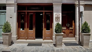 A building facade with double wooden doors, a stone plaque, and two potted plants. - Antica Dimora Suites (Rethymno)