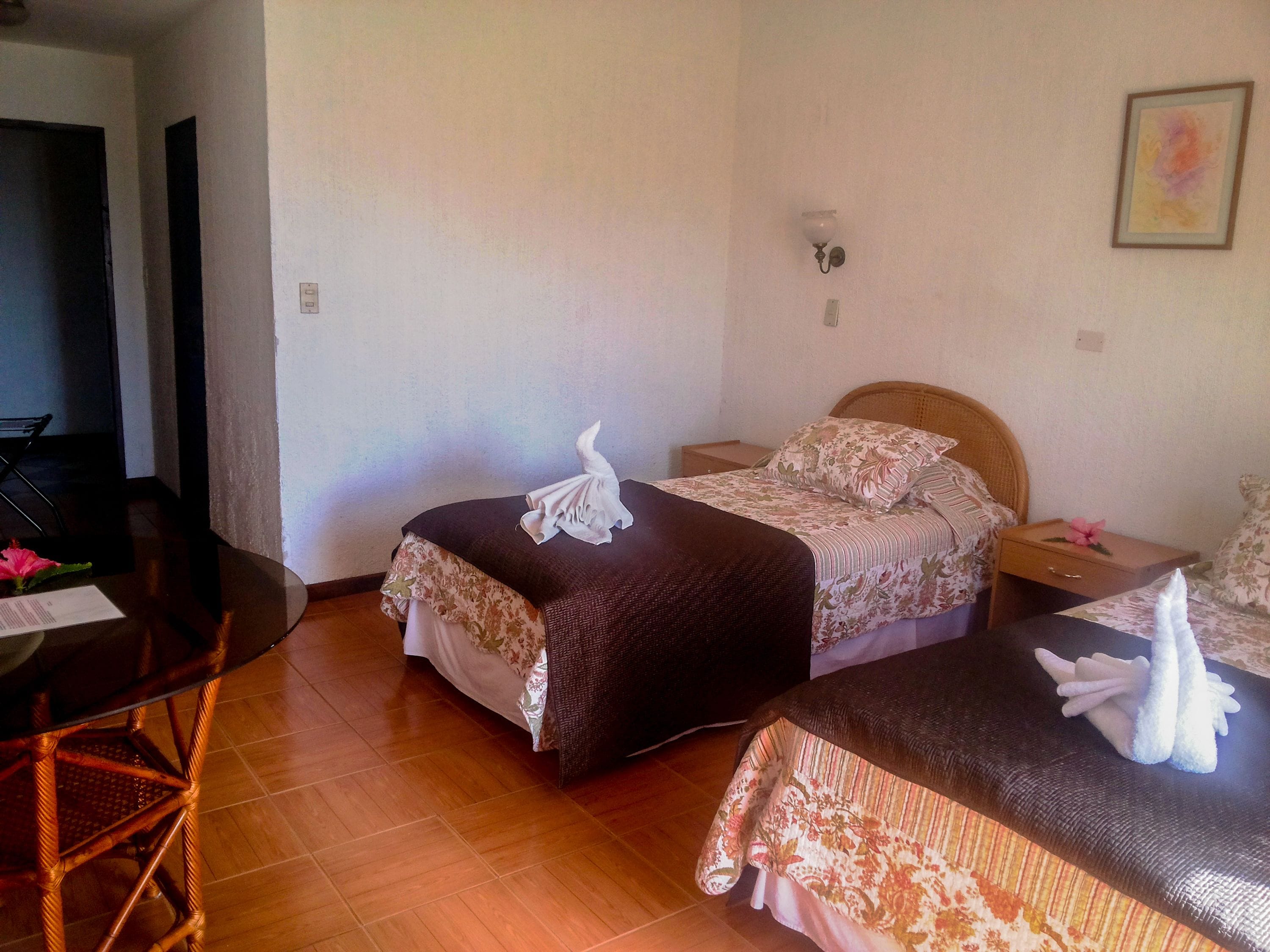 A hotel room with a bed, a wooden table, and a chair.