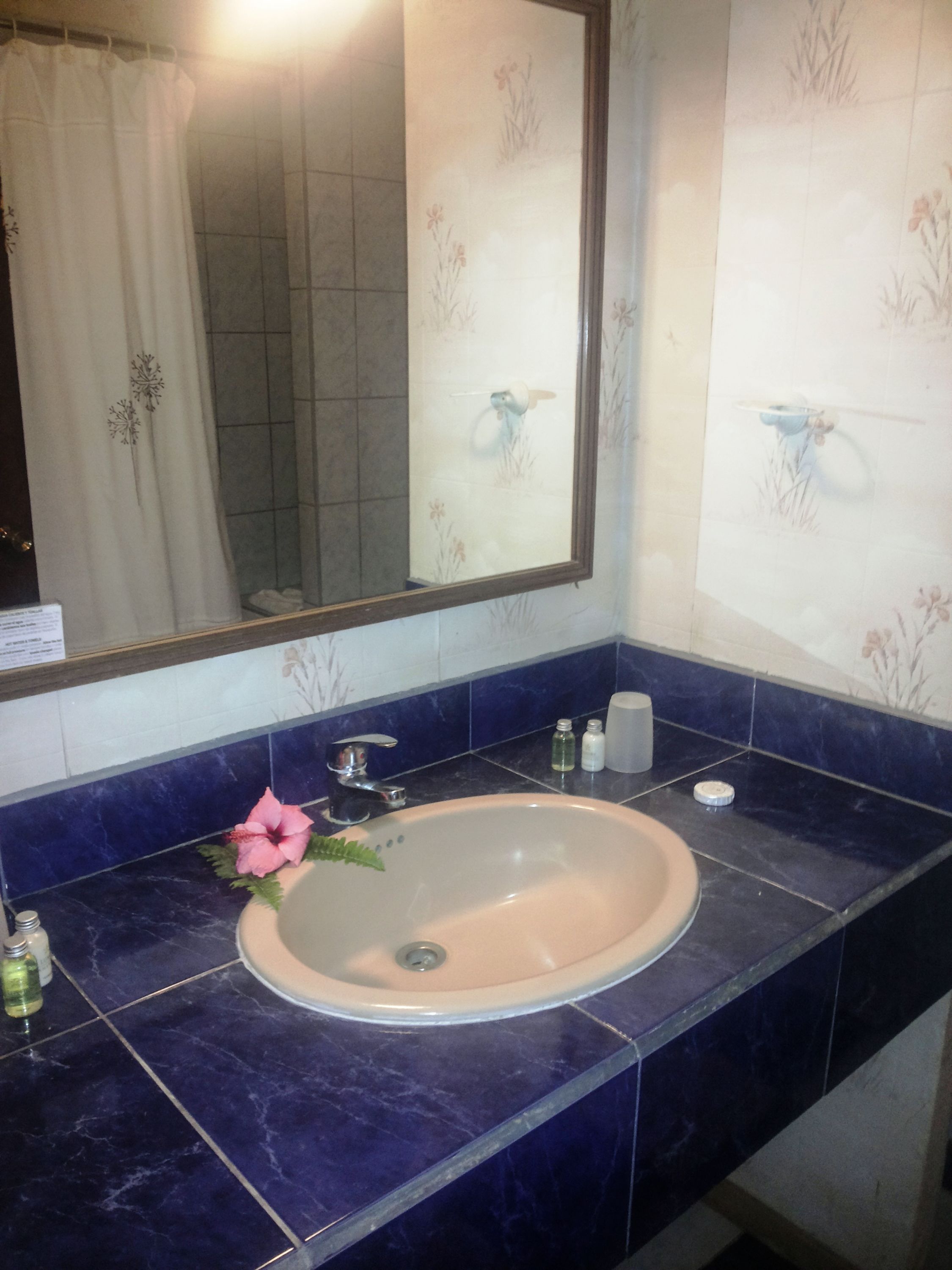 Un baño con lavamanos, espejo y azulejos azules.
