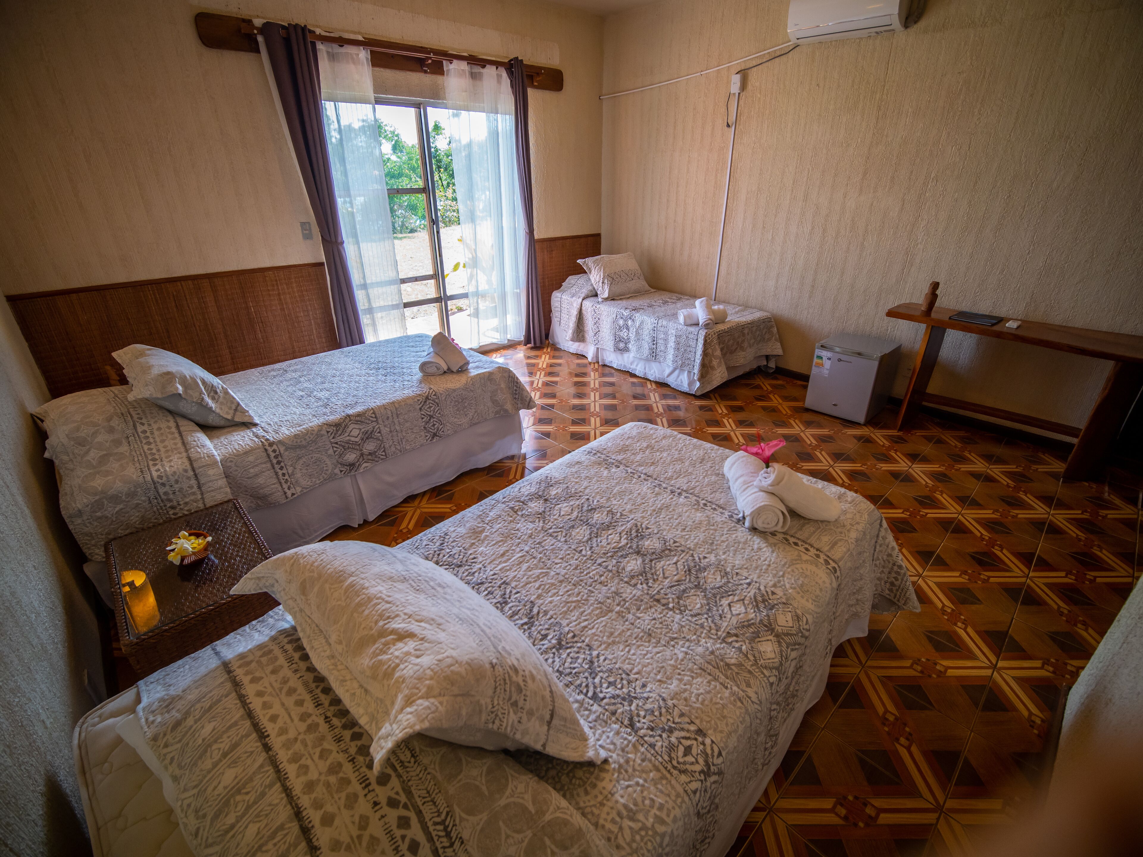A hotel room with two beds, a small table with a flower, and a desk with a chair.