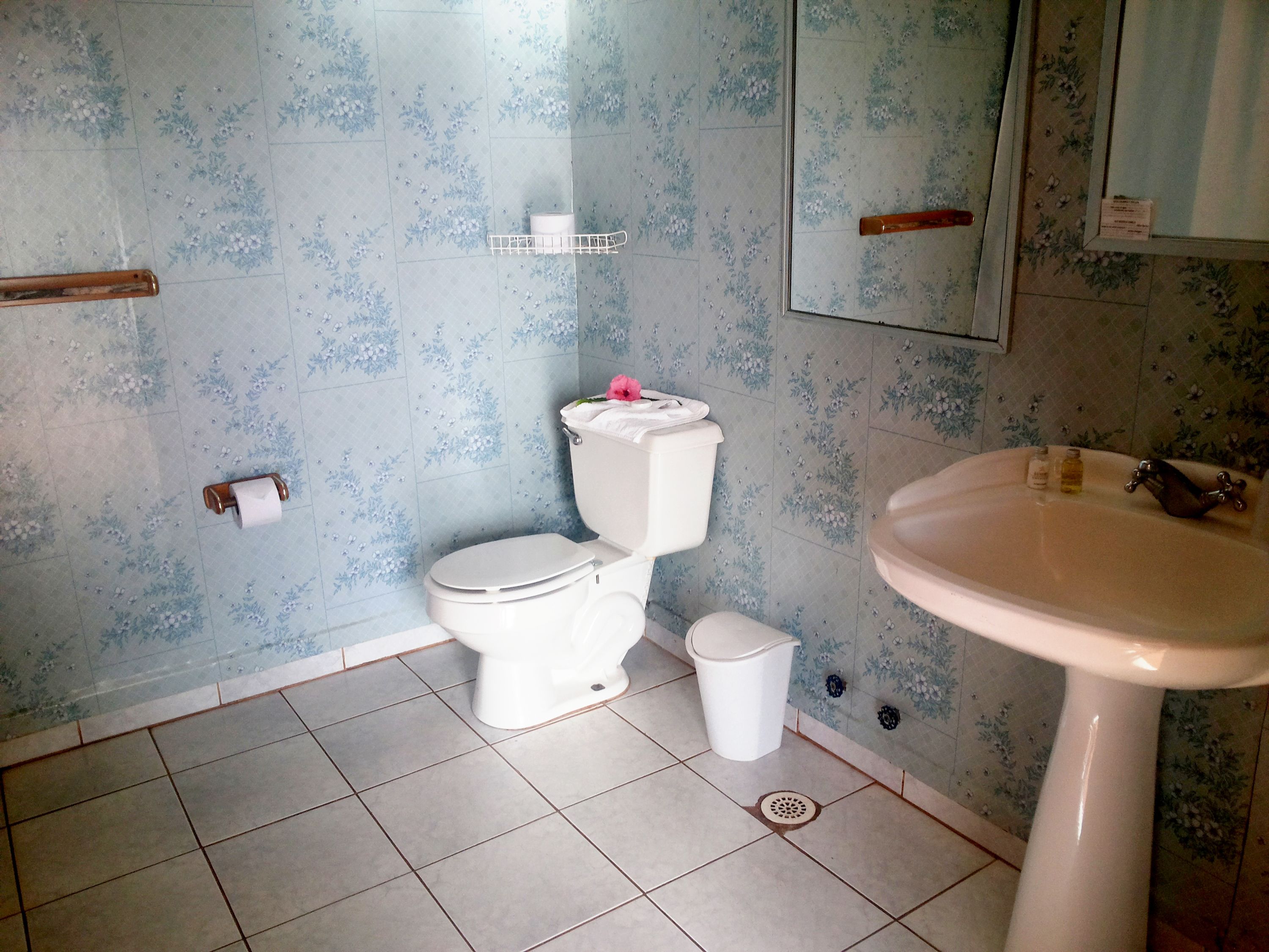 A bathroom with a toilet, sink, and tiled floor.