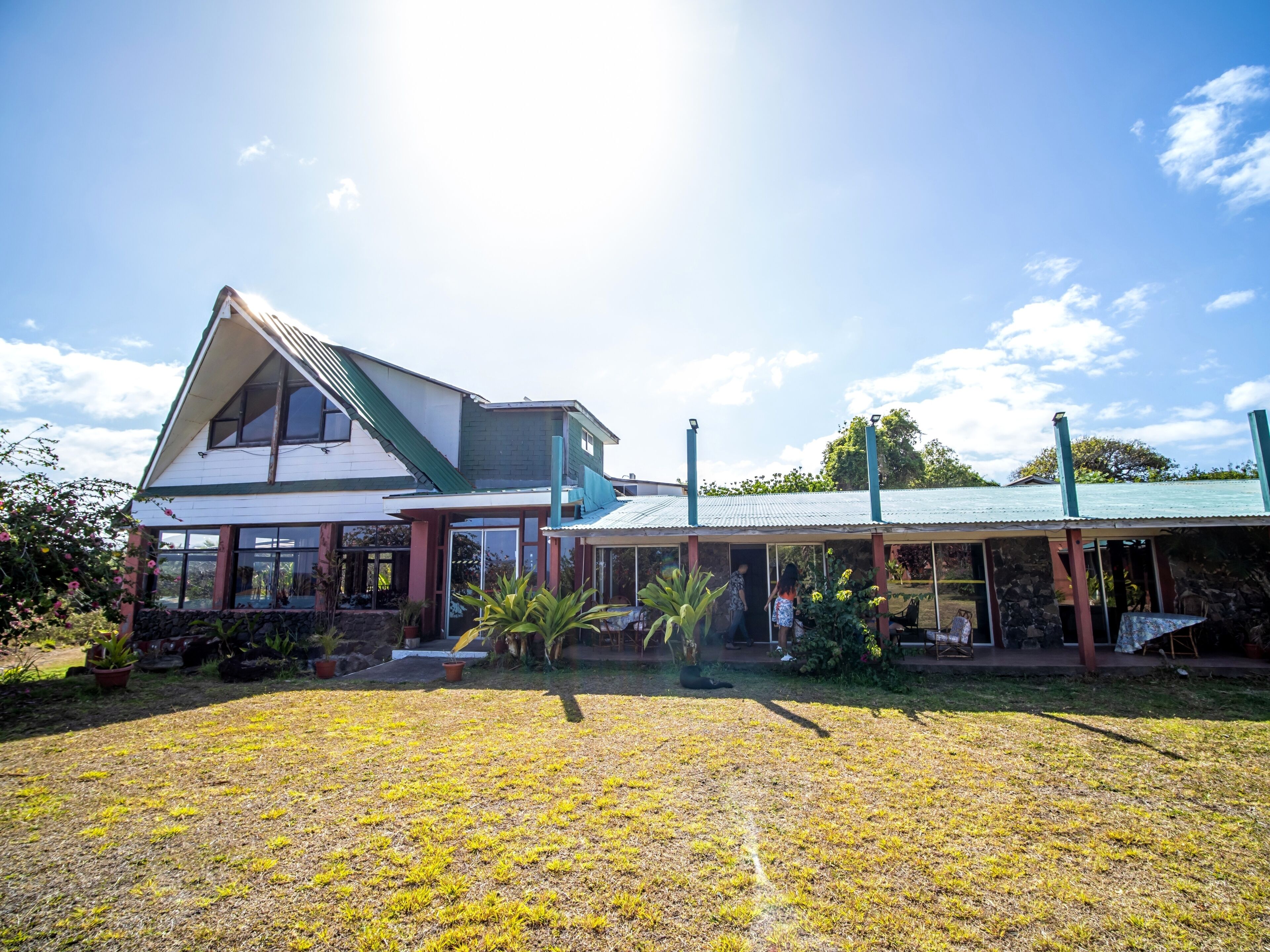 A two-story house with a green roof and a covered porch area.