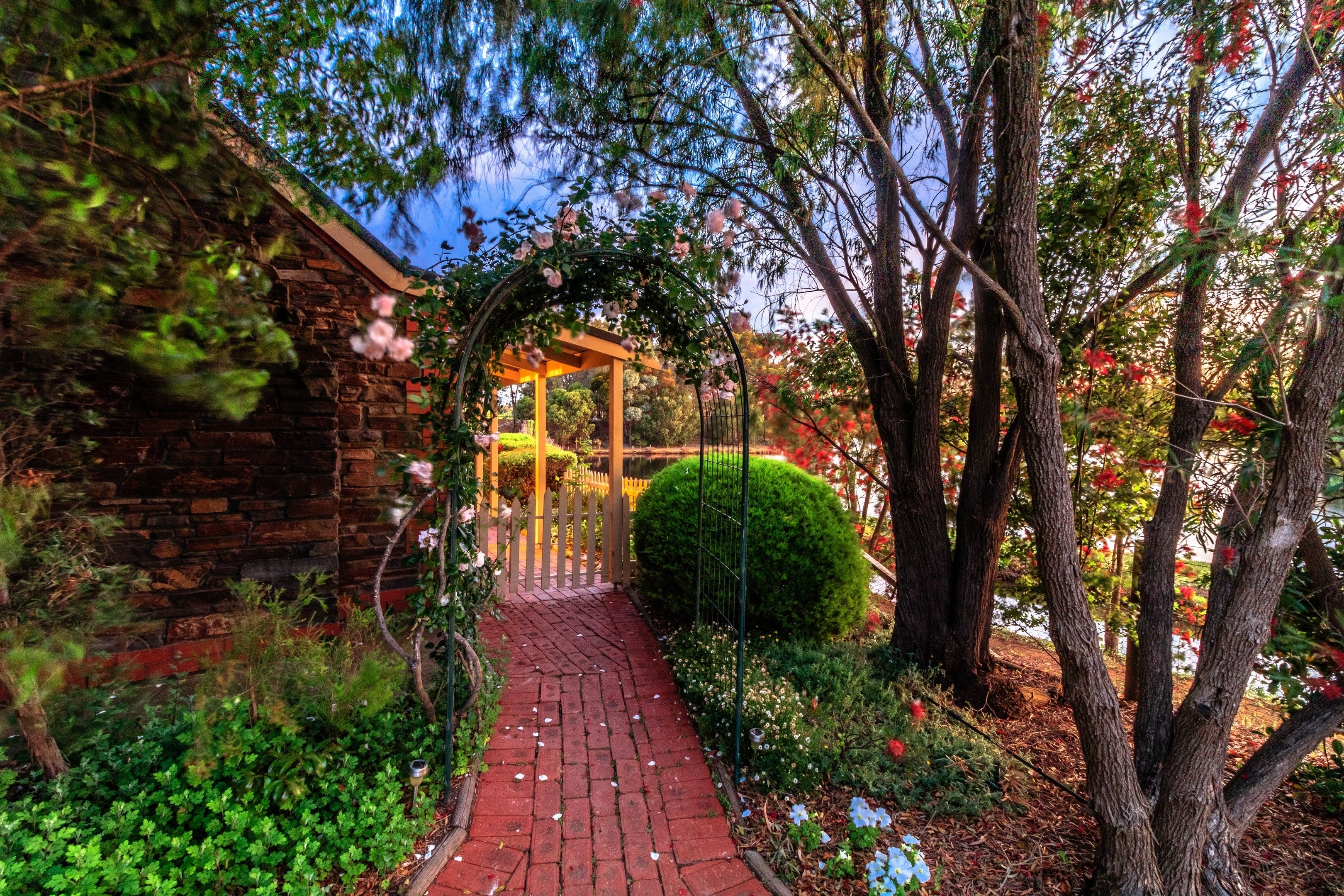 A garden pathway leading to a wooden gazebo with a stone wall on one side.