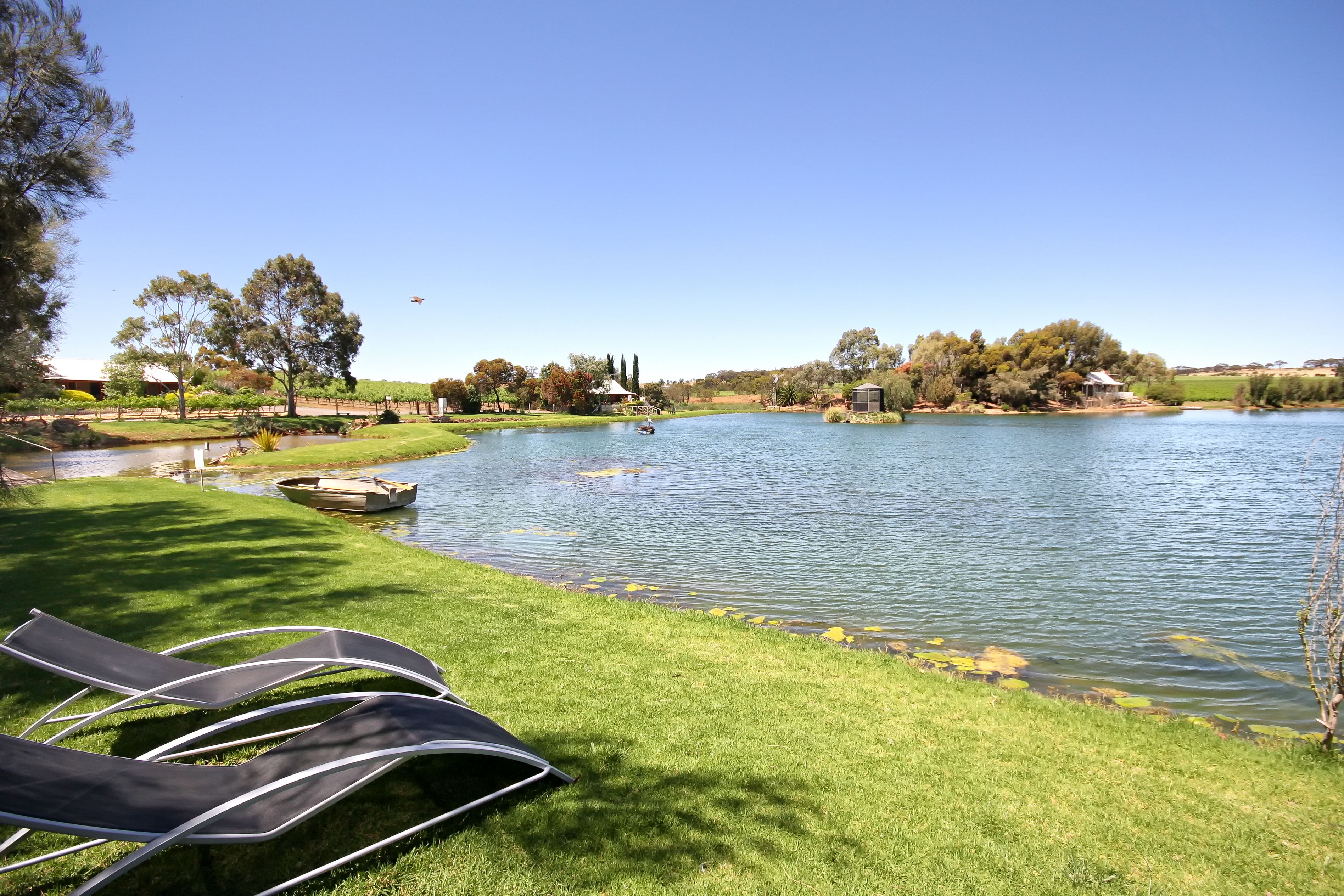 A lakeside view with lounge chairs, a boat, and a small dock.