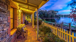 A covered patio with a brick wall, a bench, and a view of a lake at dusk.