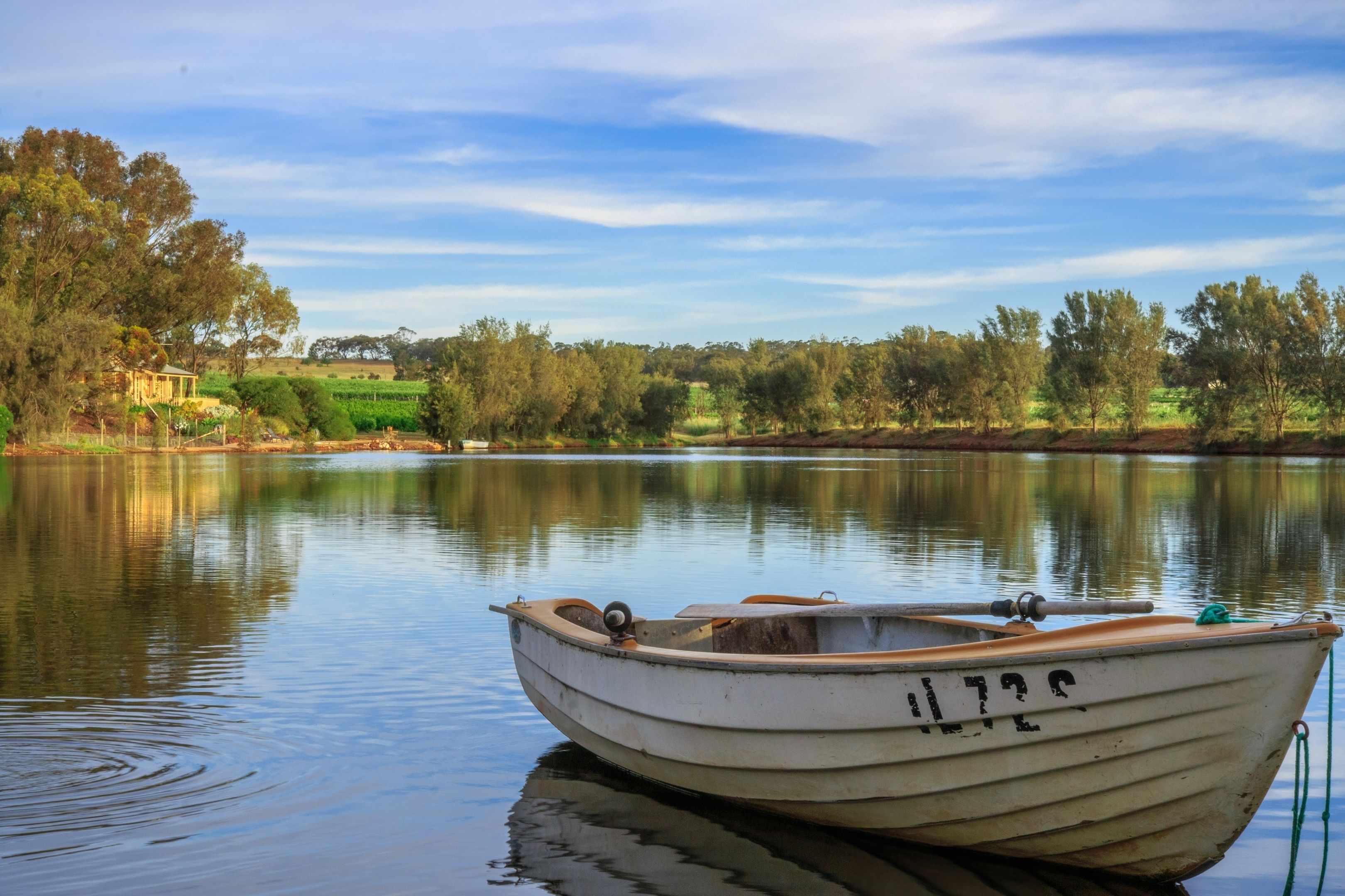 A small rowboat with the number 1722 on its side, docked on calm water.