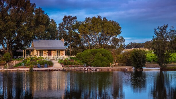 A house with a fenced garden and a pond.