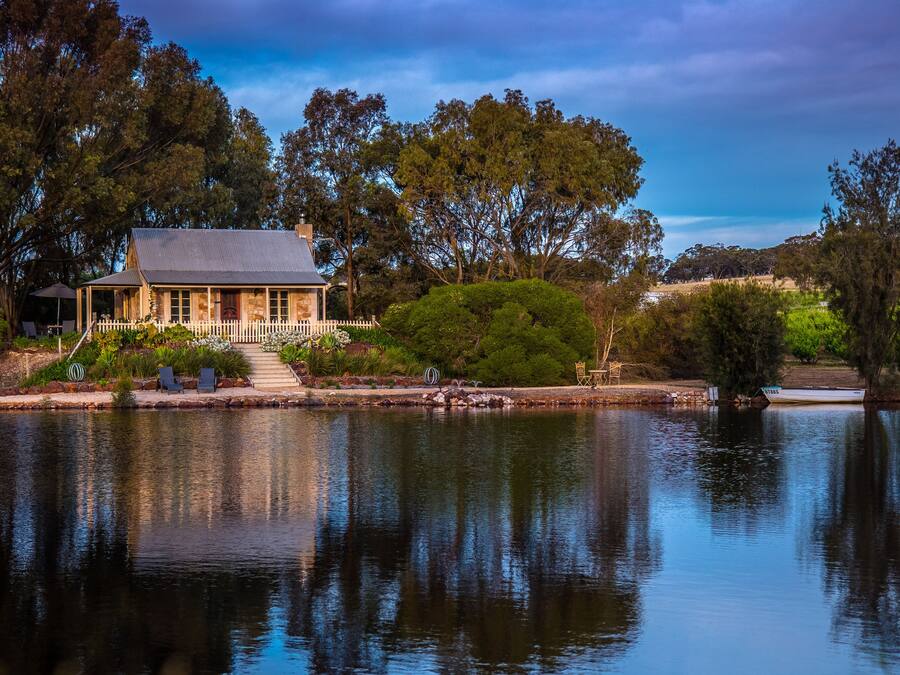A house with a fenced garden and a pond.