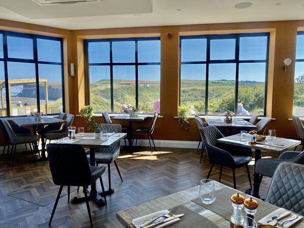 A restaurant with large windows offering a view of the countryside. Tables are set with cutlery and glasses. - The Spa Hotel (Saltburn-by-the-Sea)