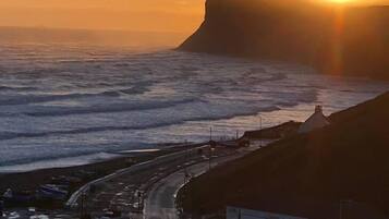 A coastal road with a cliff overlooking the ocean at sunset.