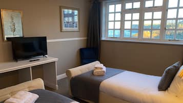 Habitación de hotel con dos camas, televisión, escritorio y ventana con vistas.