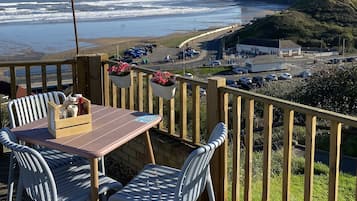 Une terrasse en bois avec une table et des chaises, offrant une vue sur la côte.