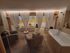 A modern bathroom with a large bathtub, a shower, and a sofa. - Penzion Janka (Brno)