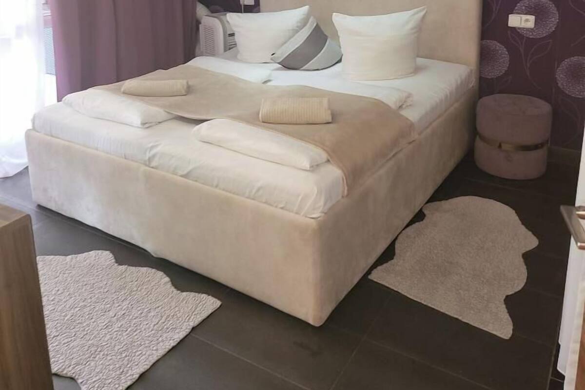 A modern bedroom with a large bed, a ceiling light fixture, and a patterned wallpaper.
