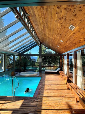 Une terrasse en bois avec une piscine, des bancs et un jacuzzi.