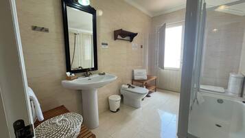 Een badkamer met een wastafel, spiegel, toilet en douche.