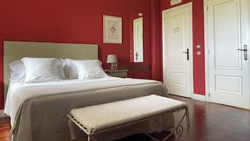 Une chambre d’hôtel comprenant un lit, une table de chevet, une lampe, un banc et deux portes.