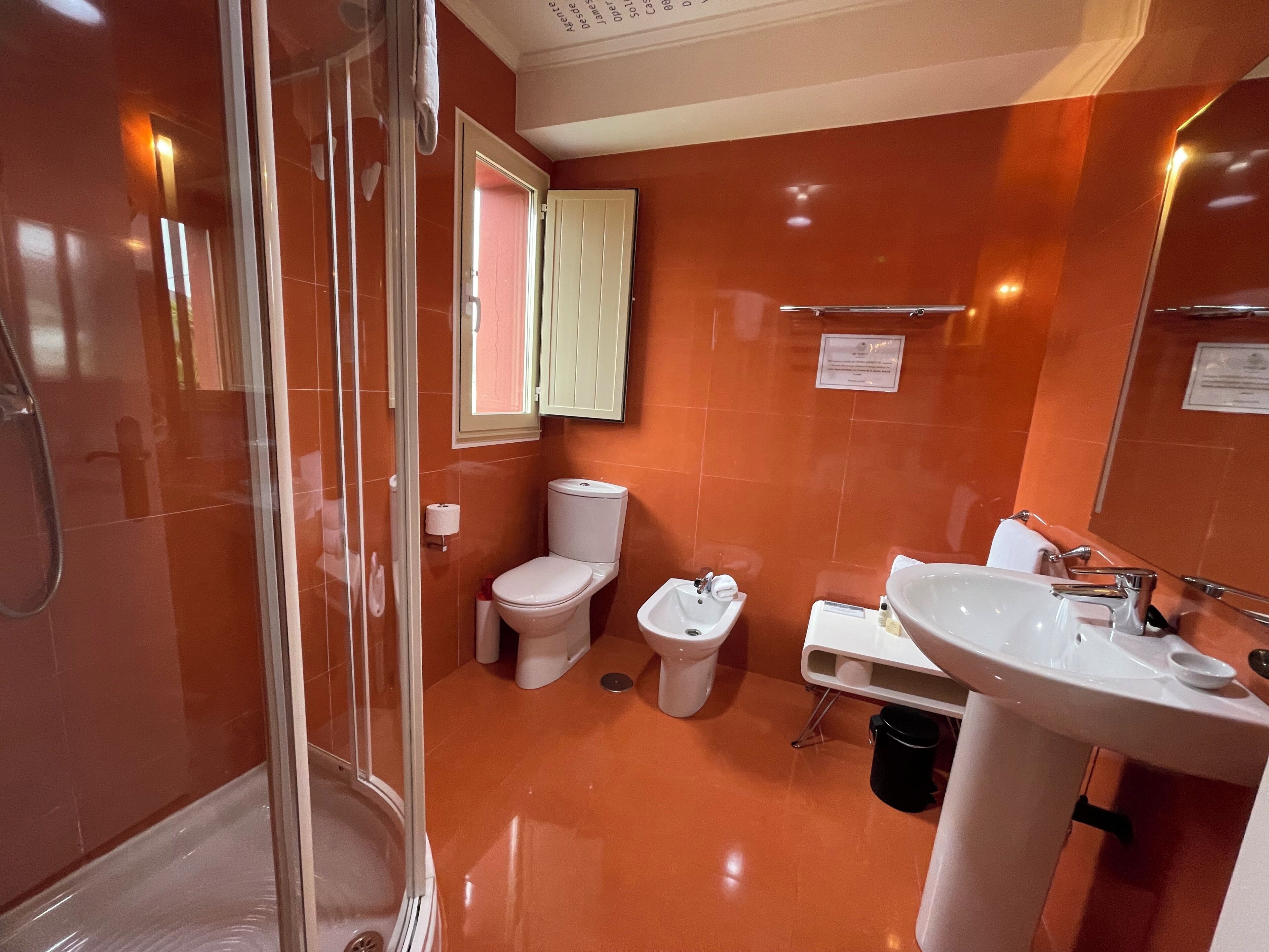 A bathroom with a glass shower enclosure, a toilet, a bidet, and a sink.