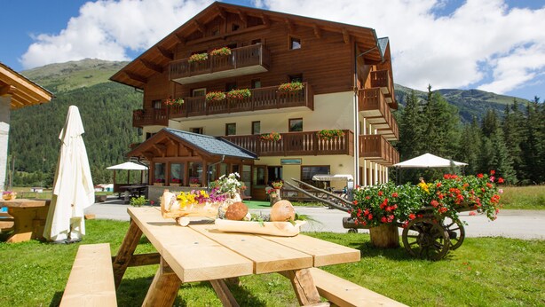 A wooden chalet with balconies, a picnic table, and flower arrangements. - Cevedale (Valfurva)