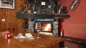 A rustic interior with a stone fireplace, wooden walls, and various historical artifacts displayed on shelves. - Cevedale (Valfurva)