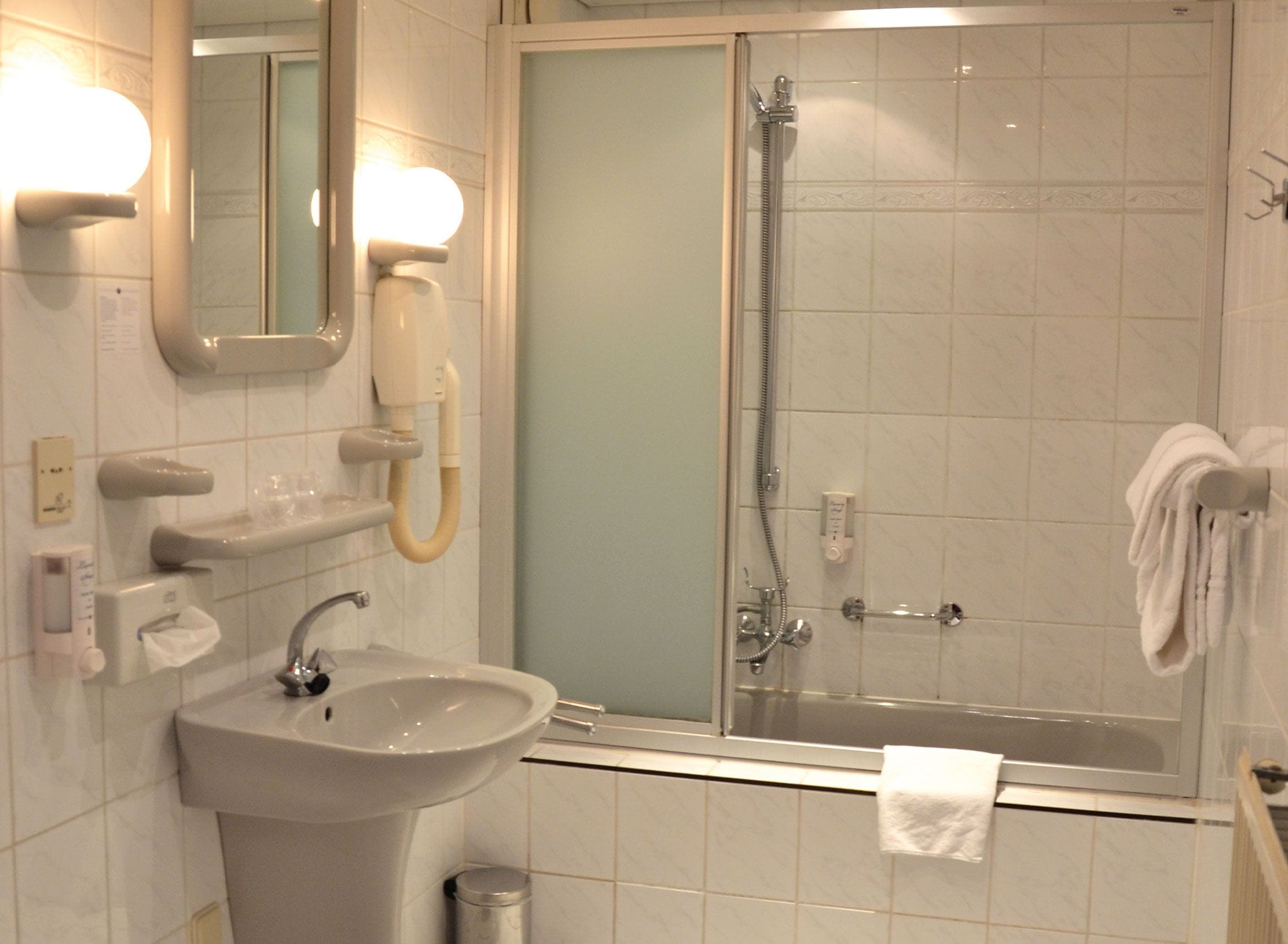 Un baño con lavamanos, espejo, toallero y cabina de ducha.
