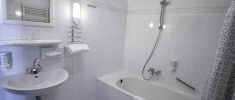 Un baño con lavamanos, espejo, toallero y zona de ducha.