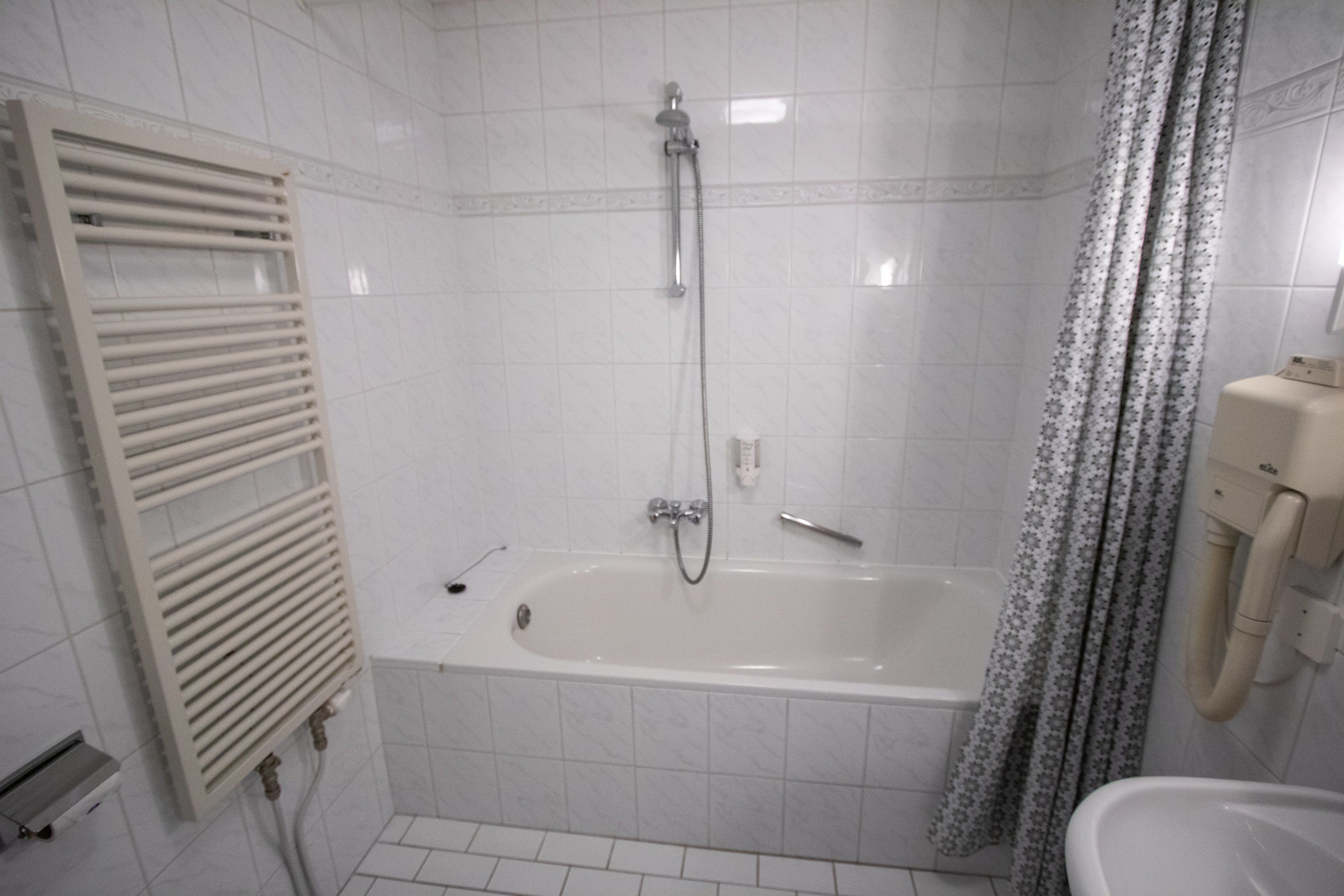 Een badkamer met een bad, een douche, een toilet en een handdoekrek.