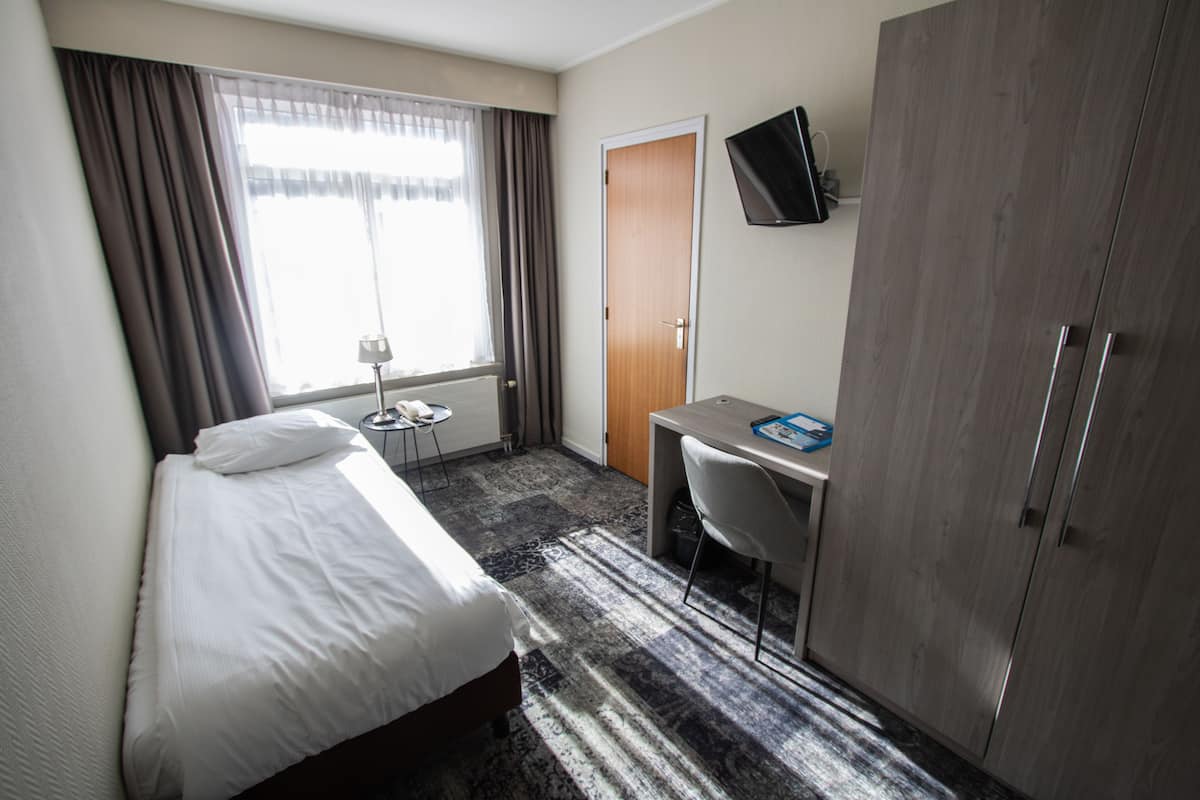 Hotellihuone, jossa on sänky, työpöytä, tuoli, televisio ja vaatekaappi.