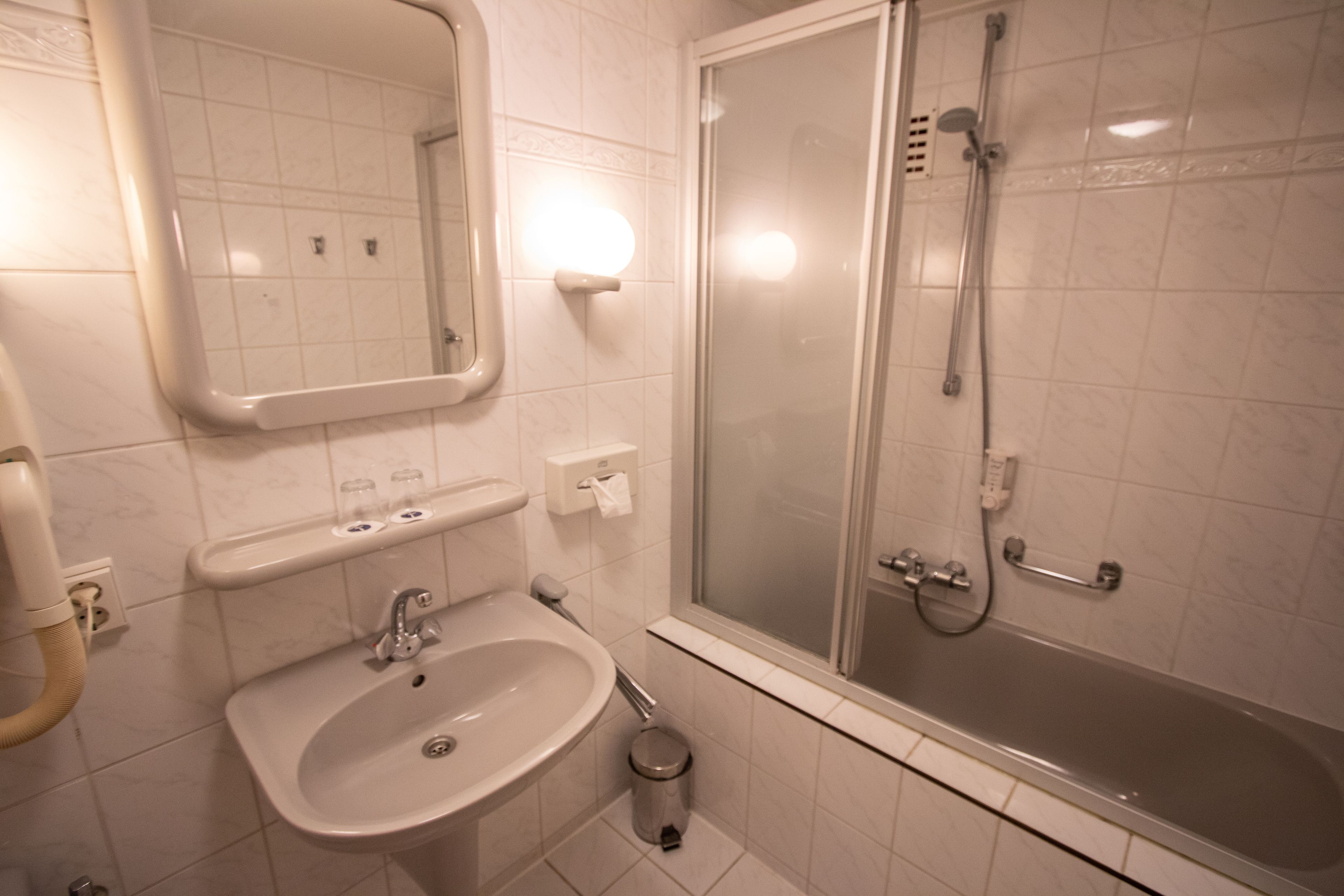 A bathroom with a sink, mirror, and a glass-enclosed shower.