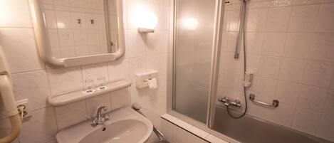 Ein Badezimmer mit Waschbecken, Spiegel und einer Duschkabine.
