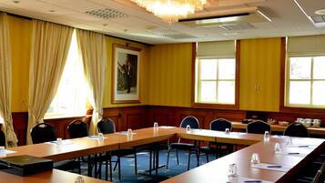 Ein Konferenzraum mit langen Tischen, Stühlen und einer Chandelier.
