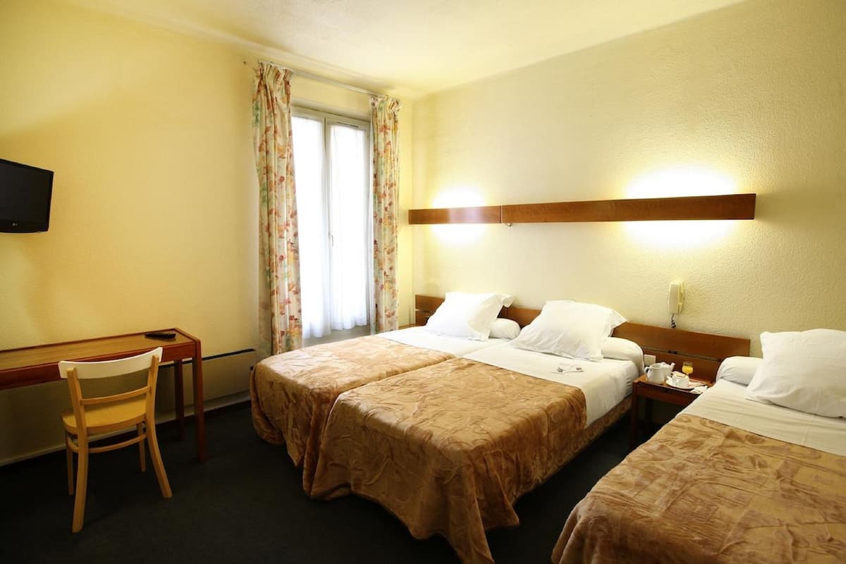 A hotel room with two beds, a desk, a chair, and a TV.