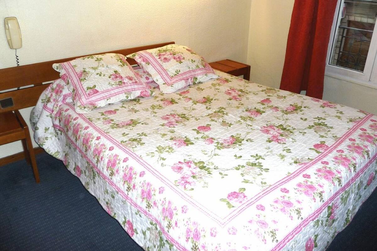 A bed with floral bedding, wooden headboard, and matching pillows.