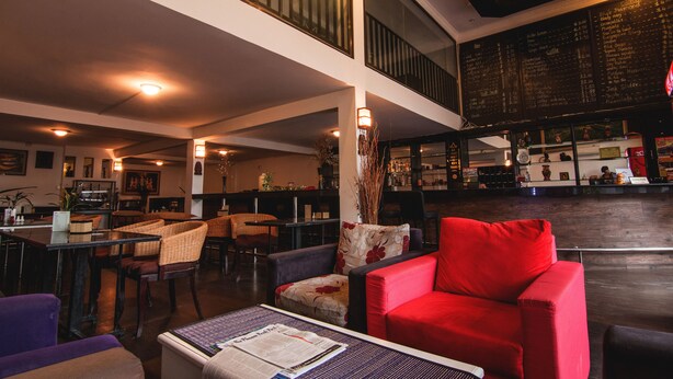 A spacious lobby with a high ceiling, a staircase, and a bar area with a menu board. - Diamond Palace Hotel (Phnom Penh)