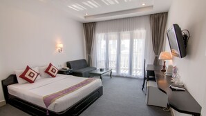 A hotel room with a bed, a desk, a chair, a TV, and a window with curtains. - Diamond Palace Hotel (Phnom Penh)