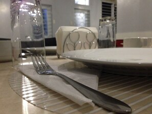 A dining table with a white plate, a fork, and a clear glass bottle. - Leesons Residences (Manila)