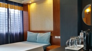 A hotel room with a bed, a bedside table with a kettle and glasses, and a mirror on the wall. - Leesons Residences (Manila)