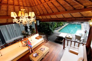 Une terrasse en bois avec une piscine, un canapé et une table.