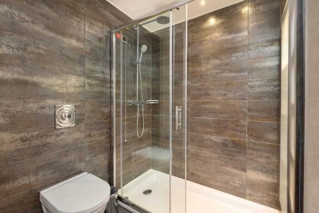 A modern bathroom with a glass-enclosed shower, a white toilet, and a wall-mounted bidet.